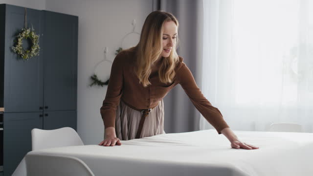 Caucasian woman laying table with a white tablecloth. Shot with RED helium camera in 8K.