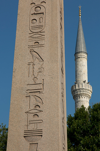 Istanbul, Turkey - July 19, 2021: The Theodosius Obelisk (Egyptian Obelisk) and the minaret of the Blue Mosque together in Istanbul's famous Sultanahmet Square. Blue sky background. History, tourism, Istanbul, building, symbol concepts.