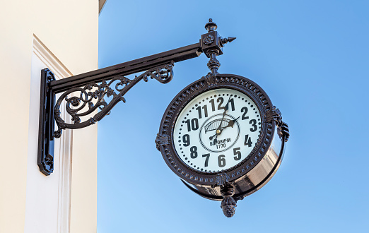 Borovichi, Russia - August 29, 2021: Big decorative street clock hanging on a wall of building
