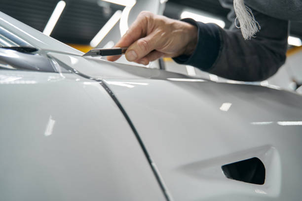 istock Professional auto detailer removing extra PPF coating from automobile 1371972415
