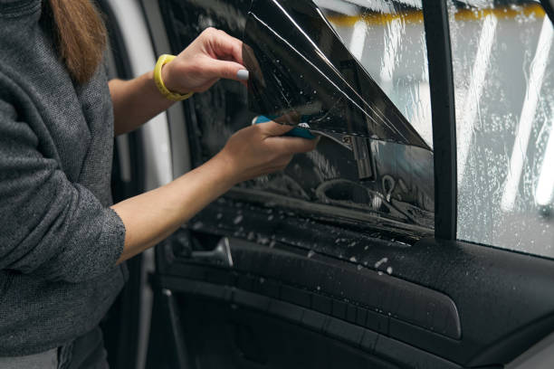 istock Service station worker fixing protective film on car windo 1371972600