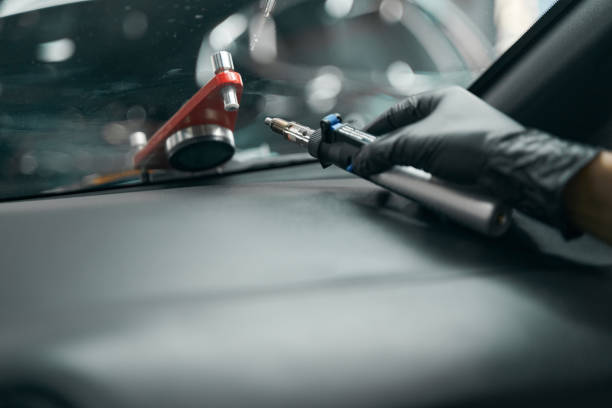istock Gloved hand with windscreen repair drill lying on dashboard cover 1371972714
