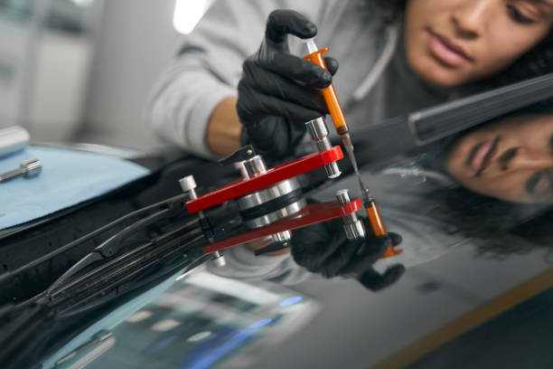 Experienced mechanic repairing cracked windshield on client vehicle