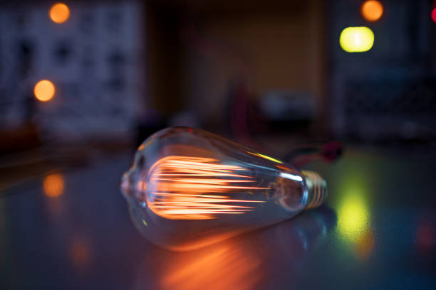 A bright fiery powerful glass incandescent lamp illuminates a dark room around with a fiery orange light