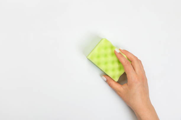 istock Housewife's hand holds a sponge for cleaning agent on a gray background. Detergent for various surfaces in the kitchen, bathroom and other rooms. 1371973195