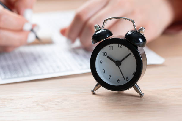 alarm clock for a student writing exams, taking an exam room with a pencil holding on an optical form of a standardized test with answers and an English piece of paper on a row chair doing the final exam in the class. despertador para un estudiante que escribe exámenes, toma una sala de examen con un lápiz sosteniendo una forma óptica de una prueba estandarizada con respuestas y un pedazo de papel en inglés en una silla de fila haciendo el examen final en la clase.