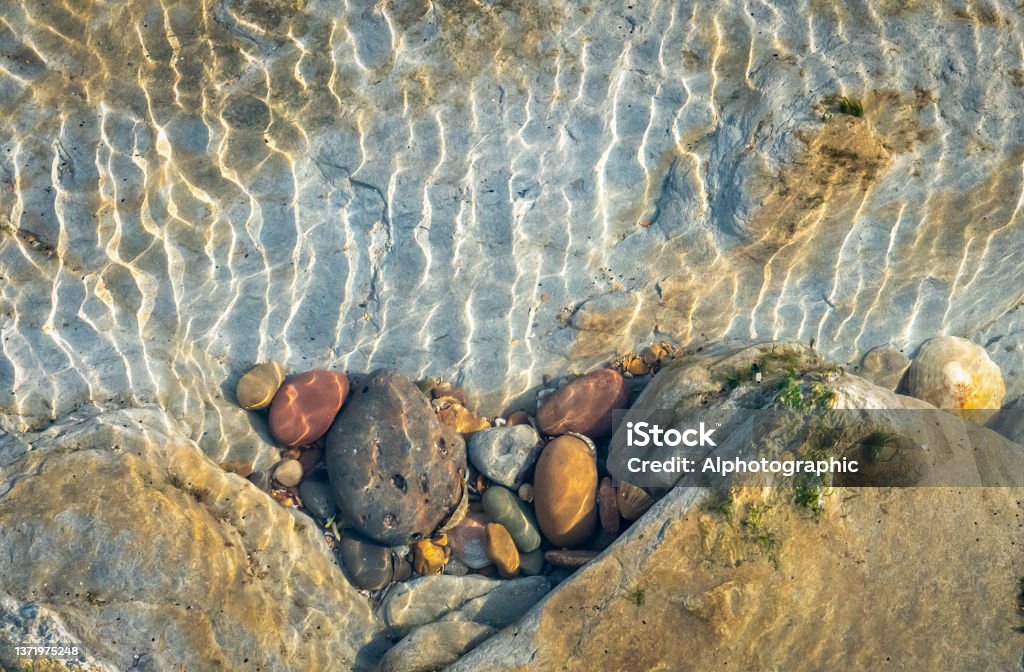 Coloured pebbles in a tidal pool in the rocks near St Mary's Island Coloured pebbles in a tidal pool in the rocks near St Mary's Island. Tidal Pool Stock Photo