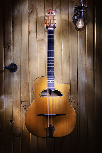 Beautifully gipsy jazz acoustic guitar details, hanged on wooden wall.