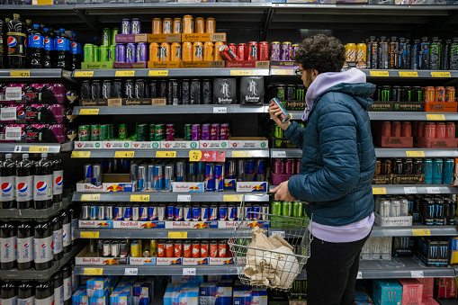 Man shopping in a supermarket while on a budget. He is looking for low prices due to inflation. He is living in the North East of England.