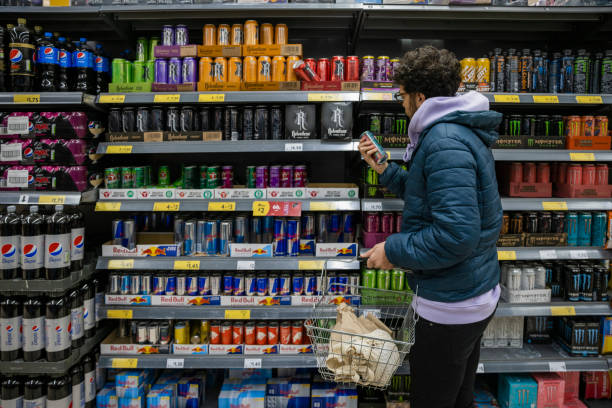 Browsing for Deals Man shopping in a supermarket while on a budget. He is looking for low prices due to inflation. He is living in the North East of England. energy drink stock pictures, royalty-free photos & images