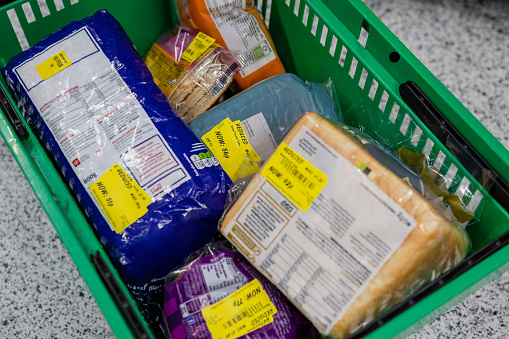 Close up of shopping basket with multiple products with yellow reduced stickers on them in the North East of England.