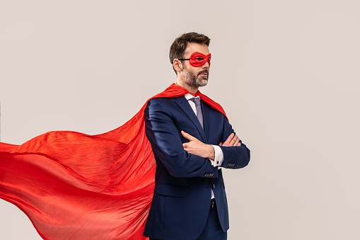 Super hero in red mask and cape posing. Studio background.  Helping hands. Handsome successful businessman. A lot of copy space.