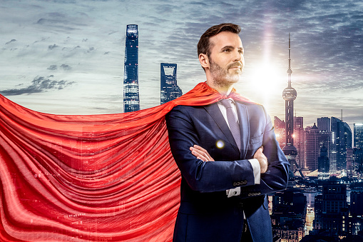 Super elegant hero in red cape posing. City on the background.  Helping hands. Handsome smiling successful businessman.