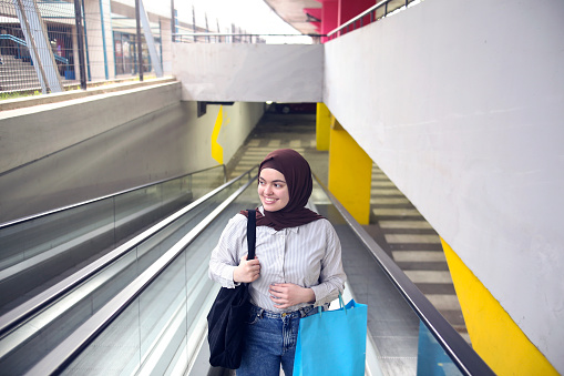 Arab woman on a moving walkway. About 25 years old, Middle-eastern female.