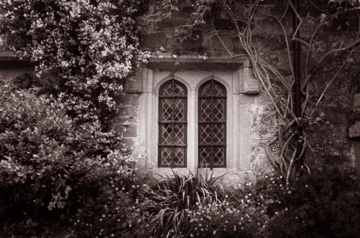 A toned monochrome image of a medieval window. Vignetting added.