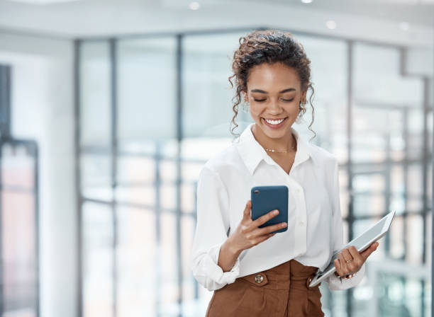 foto recortada de una atractiva joven empresaria enviando un mensaje de texto mientras trabajaba en su oficina - using laptop laptop women business fotografías e imágenes de stock