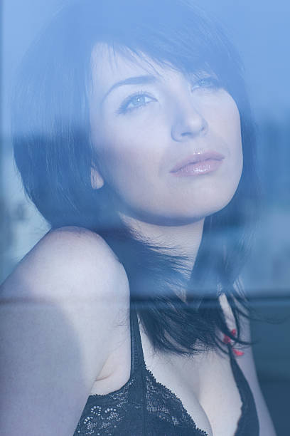 istock young woman looking through the window 137198924