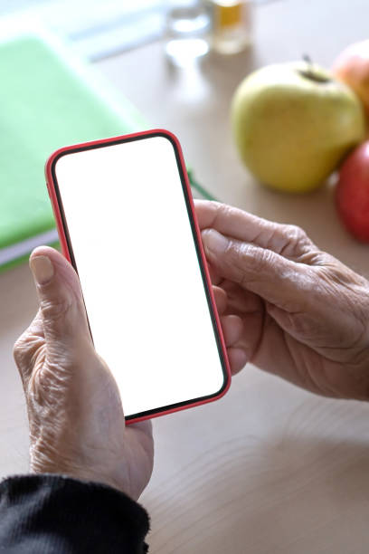 istock Hands of an elderly man holding a cell phone with a white screen, close-up 1371990233