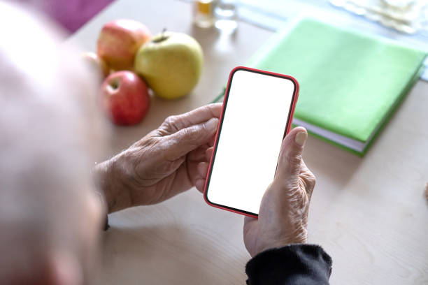 istock Hands of an elderly man holding a cell phone with a white screen, close-up 1371990239