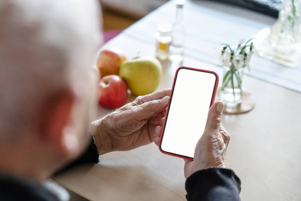 istock Hands of an elderly man holding a cell phone with a white screen, close-up 1371990242
