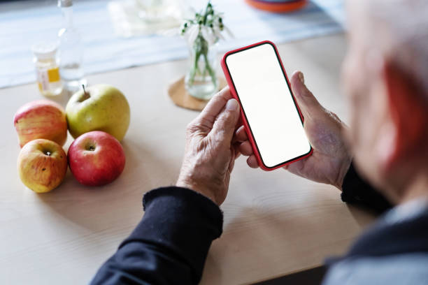 istock Hands of an elderly man holding a cell phone with a white screen, close-up 1371990244