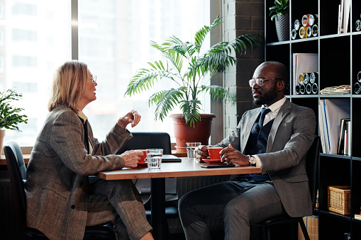 Business couple discussing business deal while drinking coffee at the table during meeting at restaurant