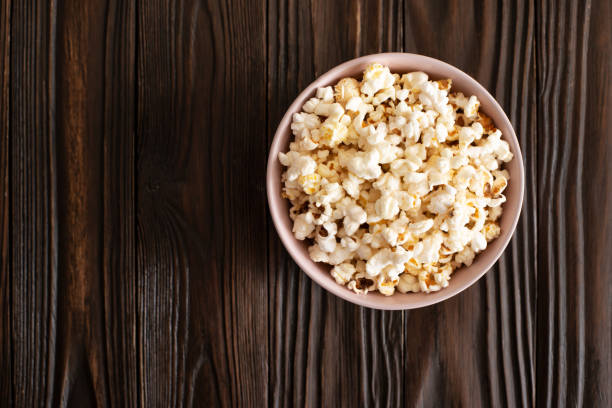 miska z popcornem na ciemnym drewnianym stole z płaskim widokiem na przestrzeń kopiowania - popcorn snack bowl corn zdjęcia i obrazy z banku zdjęć