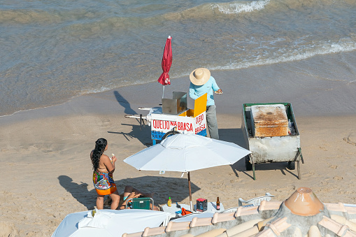 Ipojuca, PE, Brazil - October 15, 2021: man selling grilled cheese and drinks on a food cart at Porto de Galinhas beach.