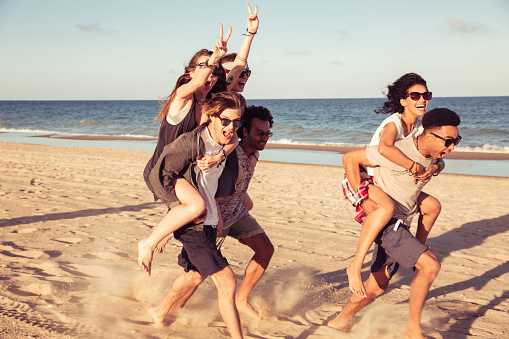 Image of happy cheerful young loving couples friends walking outdoors on the beach having fun.