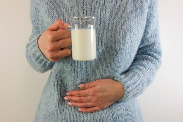 Woman with stomach ache holding glass of milk Woman with stomach ache holding glass of milk. Dairy, lactose intolerance, allergy concept lactose fermentation stock pictures, royalty-free photos & images