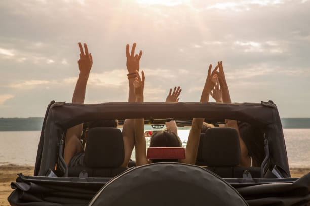 freunde sitzen mit erhobenen händen in einem auto - road trip stock-fotos und bilder