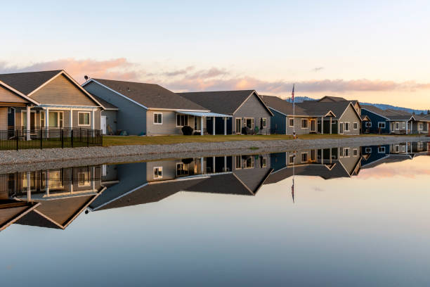 a row of similar homes in a small waterfront tract subdivision is reflected in the water in post falls, idaho, usa - tract houses imagens e fotografias de stock