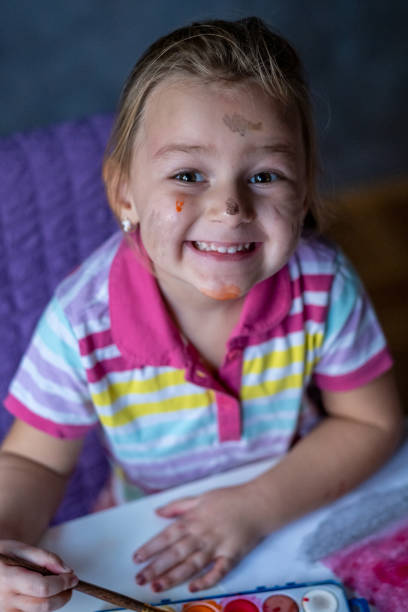 Happy cute girl drawing at home looking at camera