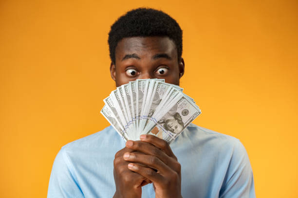 istock Excited black guy holding stack of Dollars in yellow studio 1371999194