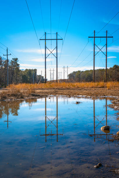 istock Electricity poles and power lines reflected on the rain puddles 1371999423