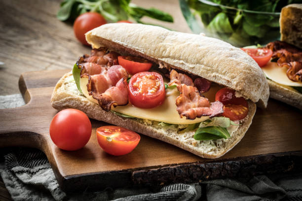 sandwich ciabatta avec fromage jaune, de bacon et salade de roquette. - ciabatta photos et images de collection