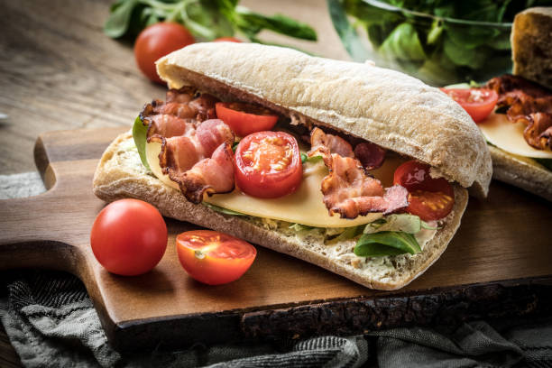 Ciabatta sandwich with arugula salad, bacon and yellow cheese. Ciabatta sandwich with arugula salad, bacon and yellow cheese on wooden board. ciabatta stock pictures, royalty-free photos & images