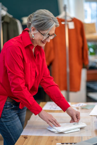 istock Woman standing sideways to camera touching packaging on table 1372000726