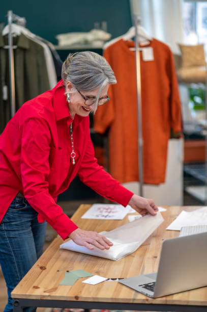 istock Satisfied woman packing clothes at table in store 1372000751
