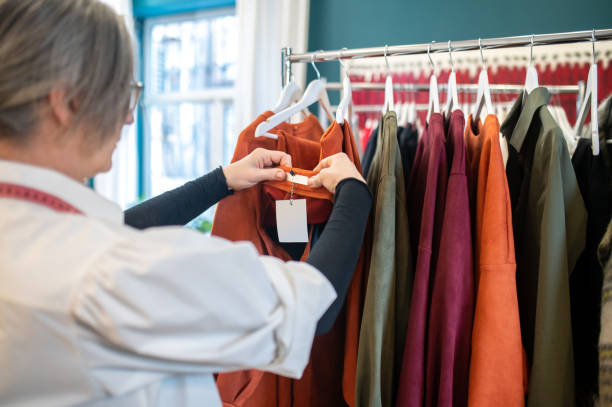 istock Woman looking at clothes tag hanging on rack 1372000998