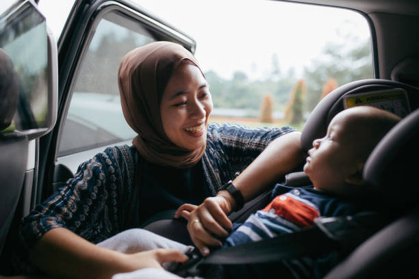 asiatische muslimische frau, die ihren babysitz anzieht - seat belt safety protection driving stock-fotos und bilder