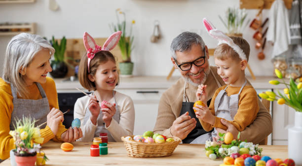 glückliche kleine kinder, die schöne bemalte eier für ostern mit liebevollen älteren großeltern kreieren - grandparent grandfather granddaughter little girls stock-fotos und bilder