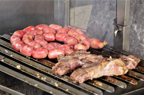 Several sausages roasting on barbecue with beef