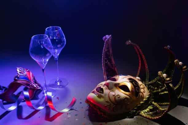 Venetian carnival masks with champagne glasses and ribbons in dark environment stock photo