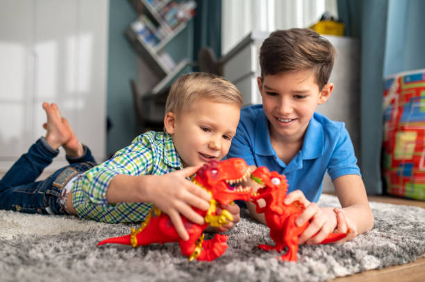 Kids acting out stories with toy dinosaurs stock photo