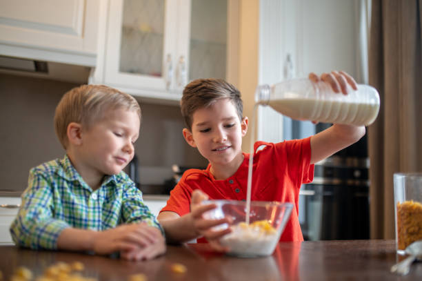 istock Concentrated kid making breakfast cereal for his brother 1372007745