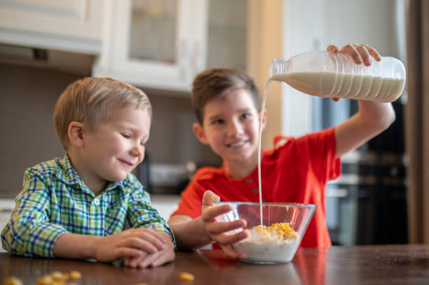 istock Cheerful boy preparing breakfast for his younger sibling 1372007747