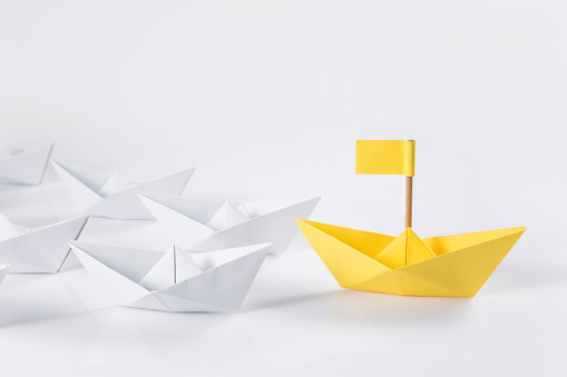 Yellow paper boat with white boats on white background