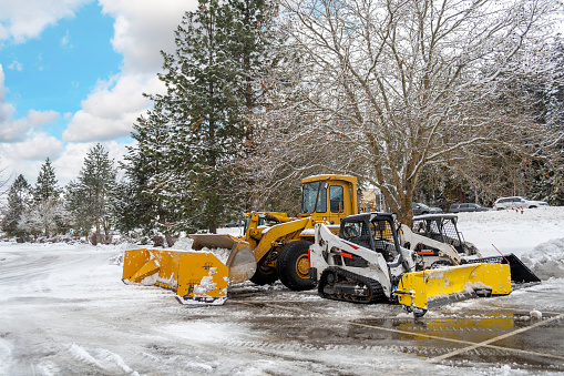 Unmarked snow plow vehicles sit empty in a parking lot after a winter storm in the mountains of North Idaho, USA.