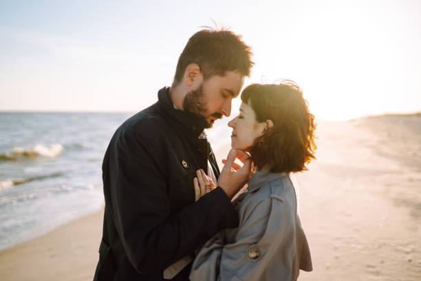 istock Stylish couple walking and hugging by the sea. Springtime. 1372010426